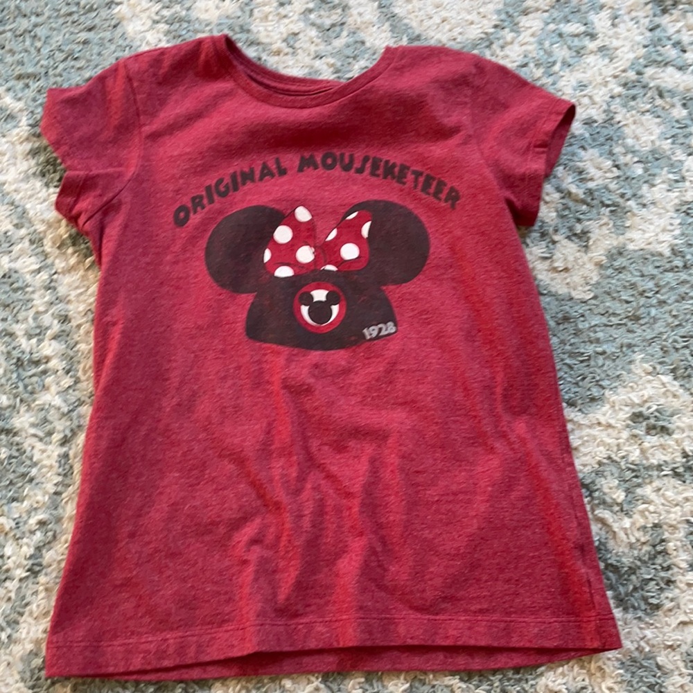 A red Disney shirt with letter on front.
